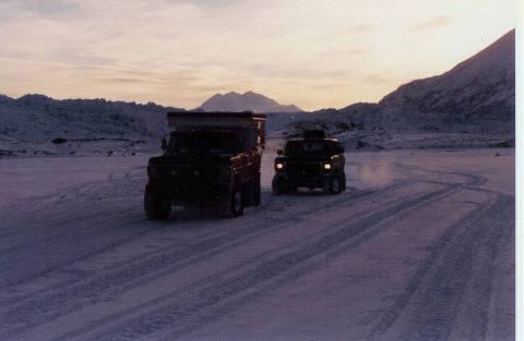 1978 Ford Bronco - Two off-road vehicles with camper tops traverse a snowy landscape under a dusky sky.