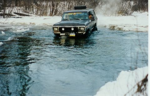 1978 Ford Bronco - A 1978 Ford Bronco navigates a watery obstacle with snow-covered terrain visible.