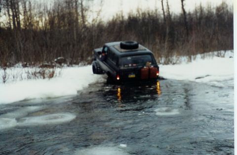 1978 Ford Bronco - SUV navigates icy water in a snowy, wooded environment.