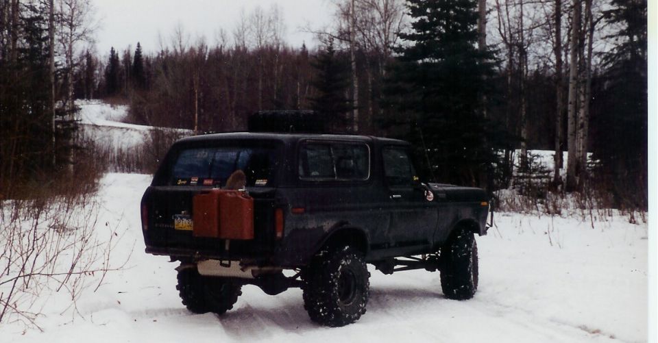 1978 Ford Bronco with auxiliary gas cans mounted on rear, parked on snowy path