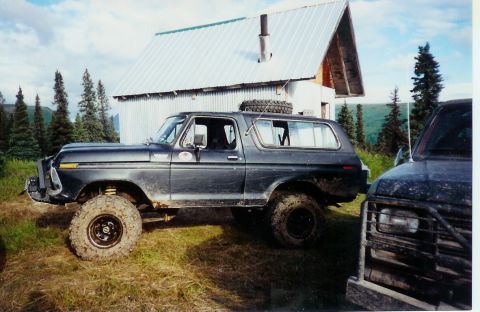 1978 Ford Bronco - This lifted 1978 Ford Bronco is parked outdoors next to another vehicle, with a metal-sided building in the background.
