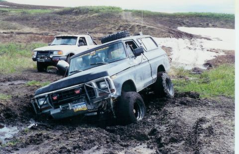 1978 Ford Bronco - Two off-road vehicles navigate a muddy trail, with one 1978 Ford Bronco deeply mired.