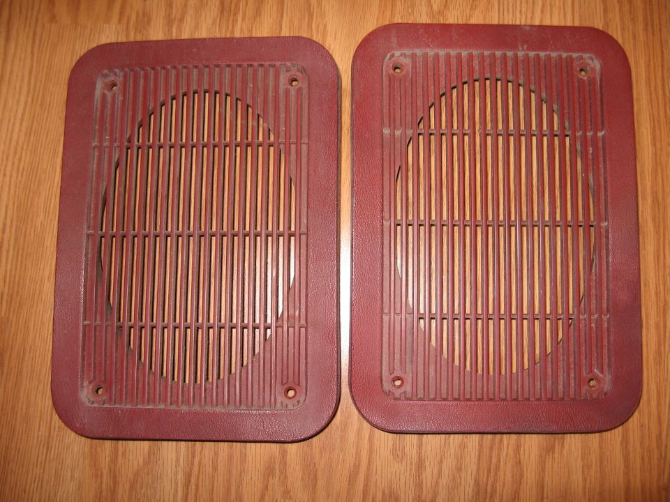 Two maroon speaker grilles with vertical slats and circular openings
