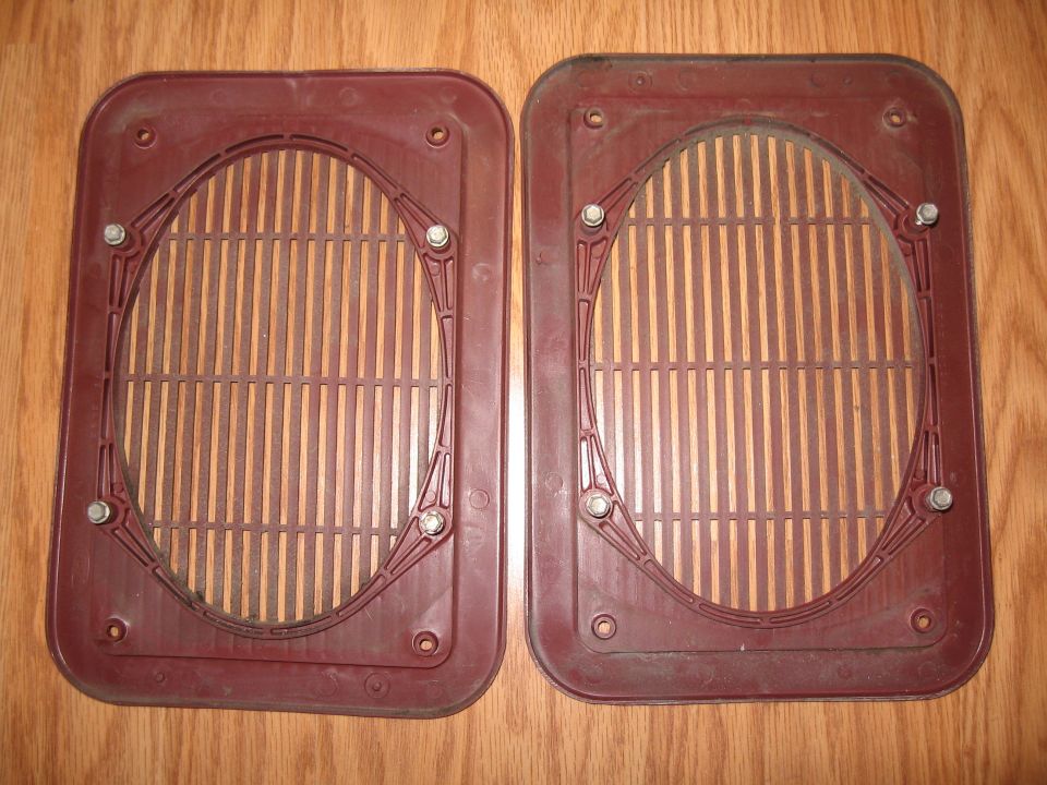 Two maroon plastic speaker grilles with vertical slats, mounted with bolts