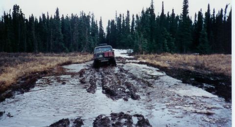 1978 Ford Bronco - A 1978 Ford Bronco navigates a muddy track through a forest.