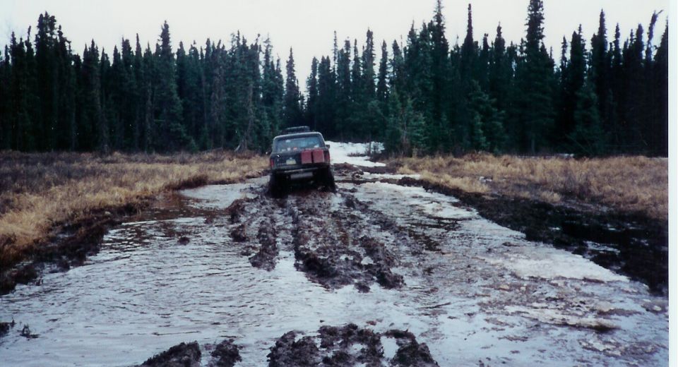 1978 Ford Bronco stuck in mud on a dirt road, rear view
