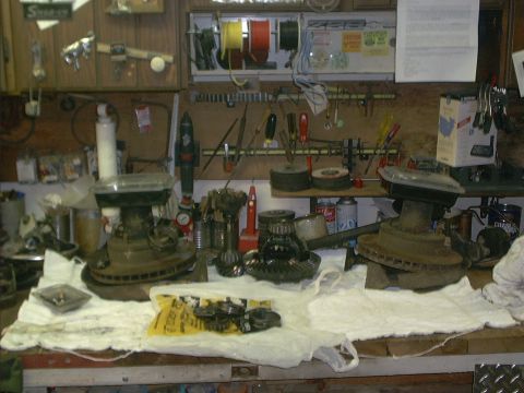1986 Ford Bronco - Workbench cluttered with automotive differential parts and tools.