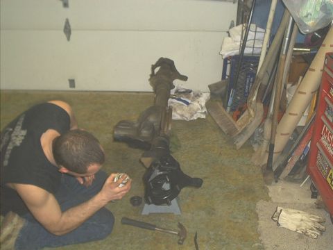 1986 Ford Bronco - A person is cleaning or preparing a vehicle's axle assembly in a garage setting with tools and storage nearby.