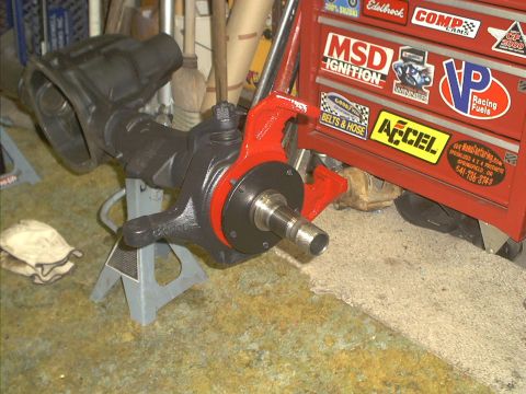 1986 Ford Bronco - A disassembled front axle assembly is shown supported by jack stands in a garage setting.