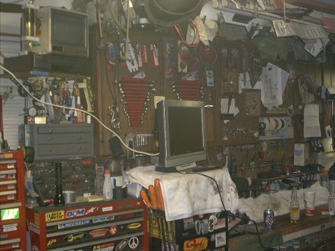 1986 Ford Bronco - A cluttered garage scene displays tool chests, a computer setup, and various tools organized on the wall.