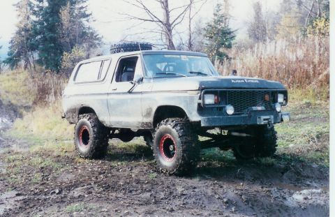 1978 Ford Bronco - A 1978 Ford Bronco is shown on a muddy, wooded trail with a spare tire mounted on the roof.