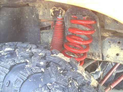 1978 Ford Bronco - Close-up view of the suspension system, a red coil spring and shock absorber.