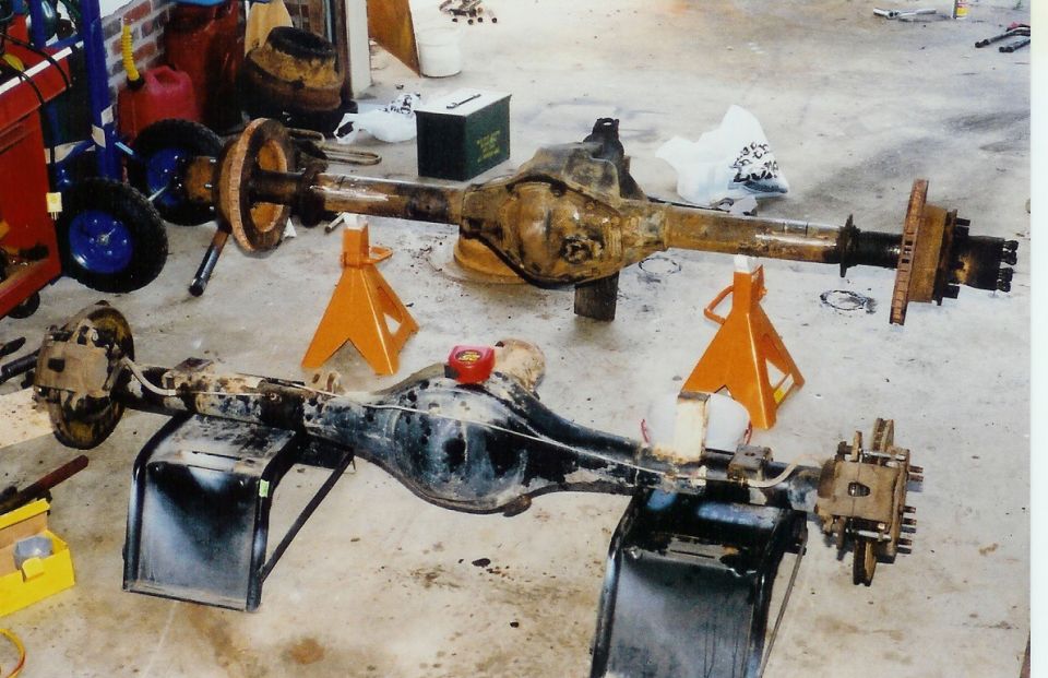 Two rusty axles on jack stands, one in front of the other