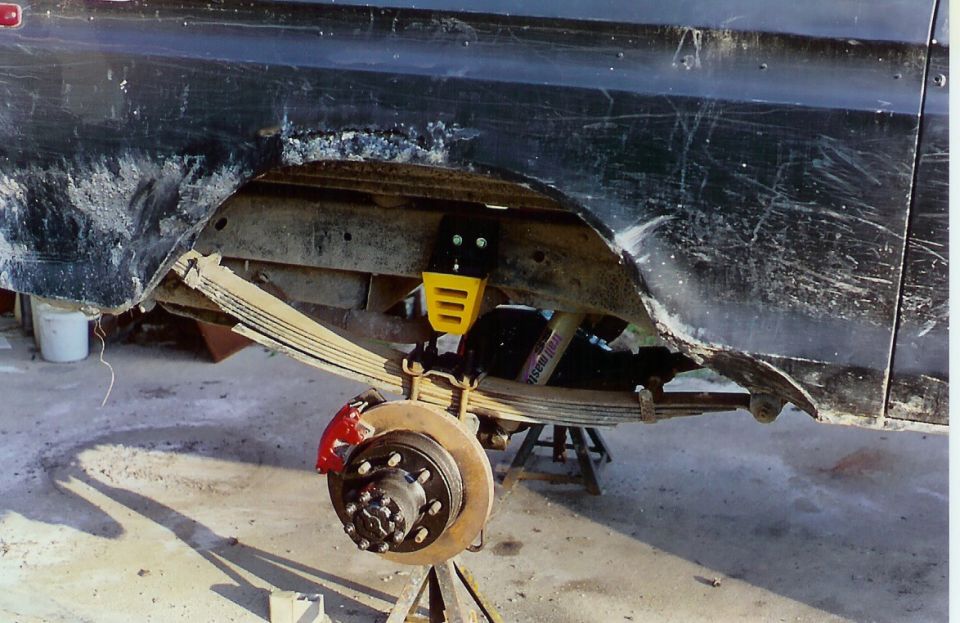 Rear leaf spring suspension with red brake caliper and yellow shock absorber mount
