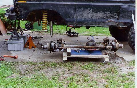 1978 Ford Bronco - Vehicle axles and suspension parts are laid out on the ground for maintenance.