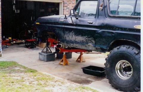 1978 Ford Bronco - 1978 Ford Bronco undergoing front-end maintenance in a garage.