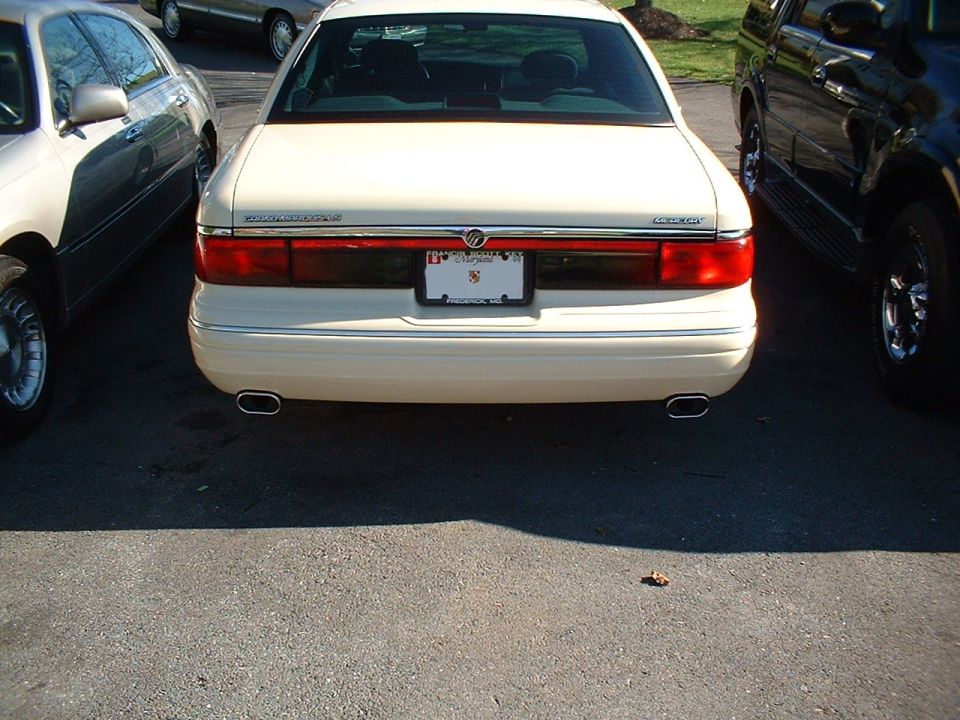 Rear of white Mercury sedan with dual exhaust and Maryland plate, parked between two vehicles