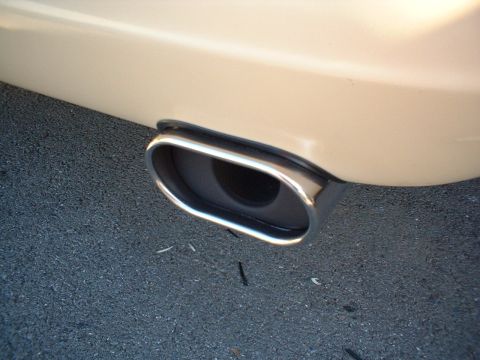 1996 Mercury Grand Marquis - Close-up of a single chrome-trimmed oblong exhaust tip on a cream-colored vehicle.