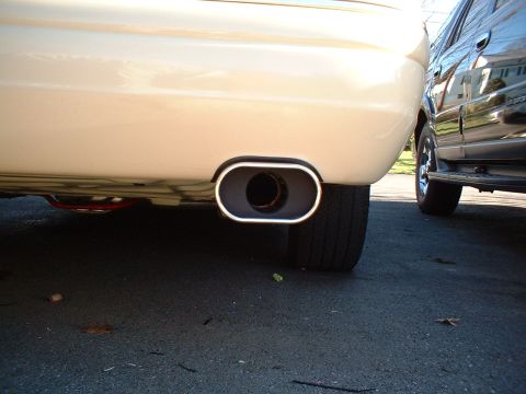 1996 Mercury Grand Marquis - A close-up view of a car's exhaust pipe, with another vehicle visible in the background.