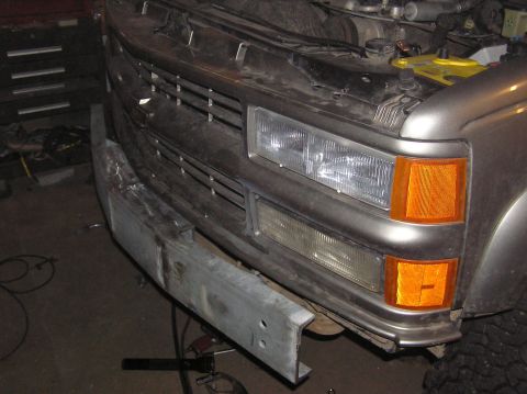 2000 Chevrolet Tahoe - A vehicle's front end shows a damaged metal bumper and a chrome grille with orange turn signals.