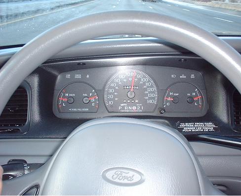 Dashboard view of a Ford Crown Victoria with a speedometer, fuel gauge, and temperature gauge. The odometer reads 143,386