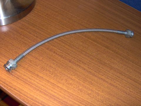 1993 Ford Probe - Braided metal hose with fittings, likely for a vehicle brake or fuel line.