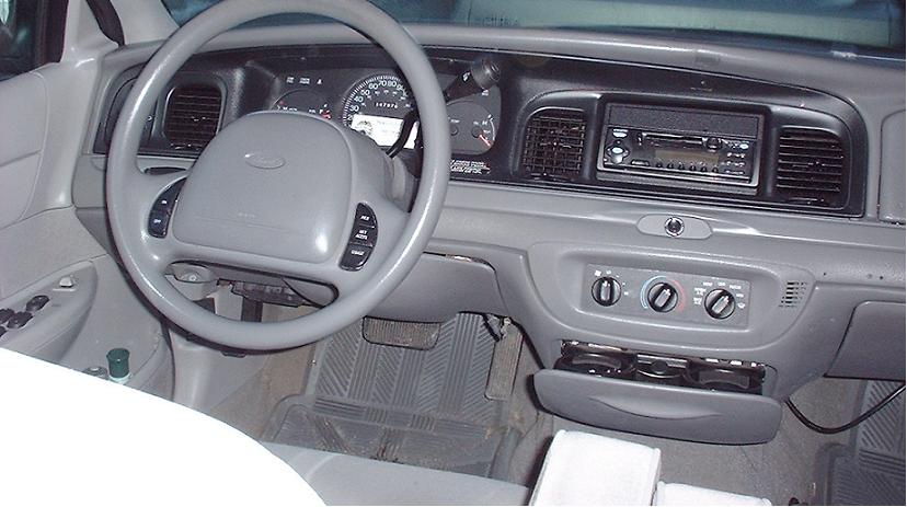 Gray dashboard and steering wheel of a 1997 Ford Crown Victoria, showing the center console with radio and climate controls