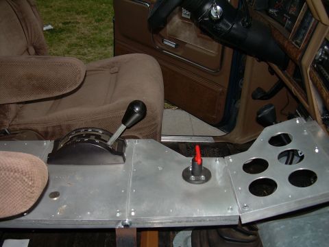1986 Ford Bronco - The custom console in this vehicle features a shifter and a red emergency lever, with circular openings for components.