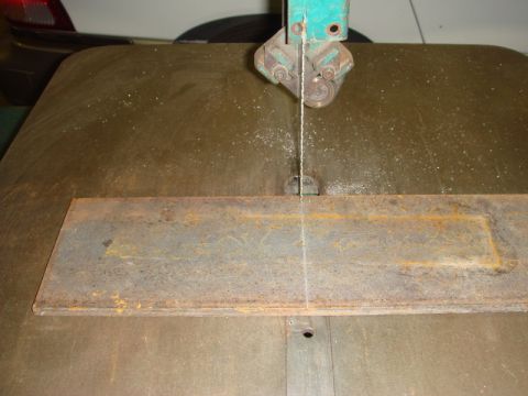 1996 Ford Bronco - A bandsaw cuts through a piece of metal, with sawdust scattered on the workbench.