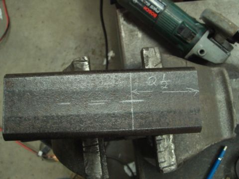 1996 Ford Bronco - A metal bar is marked for cutting with chalk measurements, held in a vise with an angle grinder nearby.