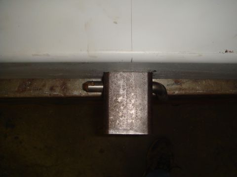 1996 Ford Bronco - Close-up view of a rear bumper latch mechanism, showing a pin and a curved pipe attachment.