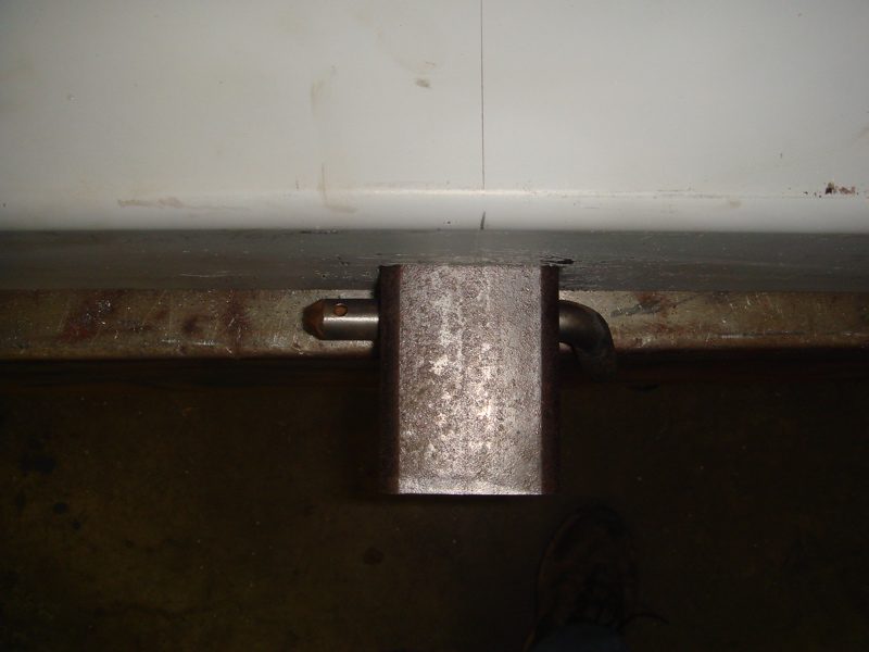 Rear bumper latch mechanism with pin and curved pipe