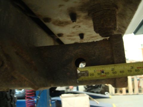 1996 Ford Bronco - A tape measure is used to gauge a dimension on the rusty undercarriage of a vehicle.
