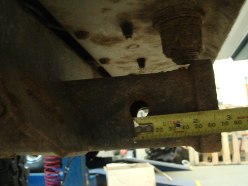 Close-up of rusty vehicle frame with a tape measure showing about 2.5 inches