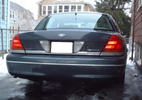 1997 Ford Crown Victoria - The rear of a Ford Crown Victoria is shown, with a blank license plate area and illuminated taillights.