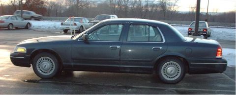 1997 Ford Crown Victoria - A dark blue 1997 Ford Crown Victoria sedan is parked outdoors, with other vehicles visible in the background.