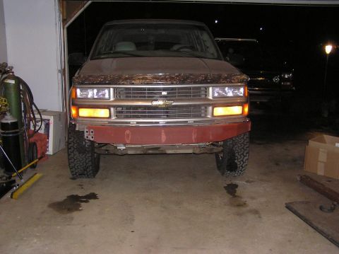 2000 Chevrolet Tahoe - The front bumper of a 1995 Chevrolet Tahoe is shown in red primer, with a second vehicle visible in the background.