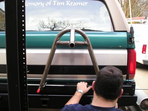 1996 Ford Bronco - A custom spare tire carrier is being fitted to the rear of a Ford Bronco, which has a memorial message on its rear window.