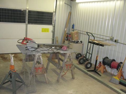 1990 Ford Bronco - A workshop scene a circular saw, sawhorses, a tool cart, and various other equipment, likely in a garage or storage area.