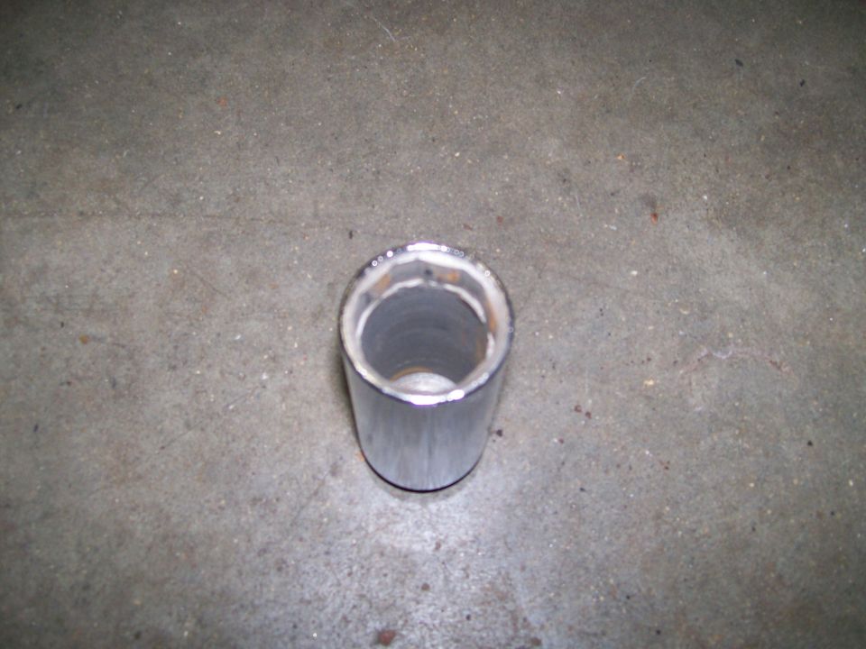 Chrome exhaust pipe with visible weld marks on the interior rim, resting on a concrete floor