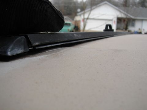1996 Ford Bronco - Detail of interior trim and fabric, with a blurred background of houses and a green vehicle.