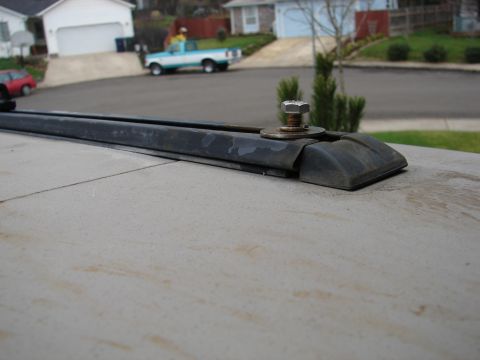 1996 Ford Bronco - A roof rack rail is shown in close-up, with a blue and white pickup truck in the background.