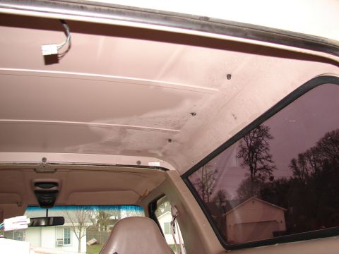 1996 Ford Bronco - The interior ceiling of a vehicle, with a view of the outside through the side window.