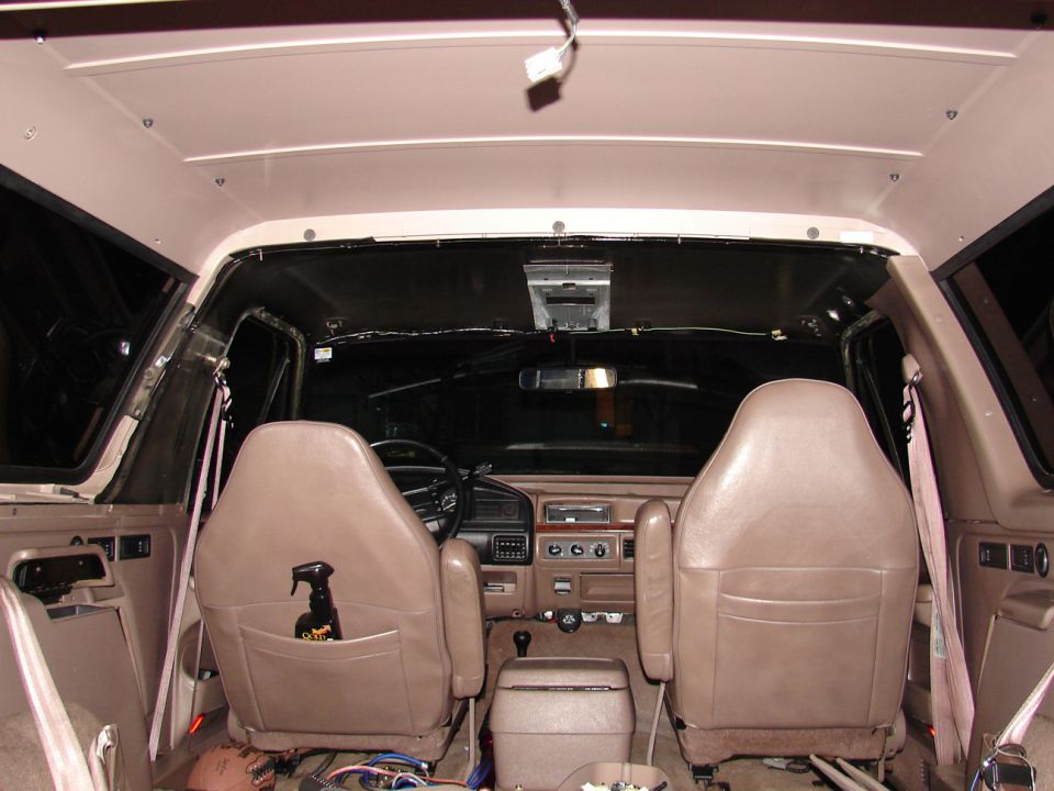 Interior rear view of a truck cab looking forward over two tan bucket seats to the dash