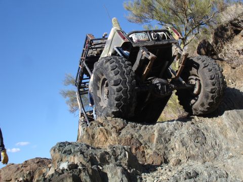 1984 Ford Bronco - Custom buggy navigates difficult rocky terrain under a clear blue sky.