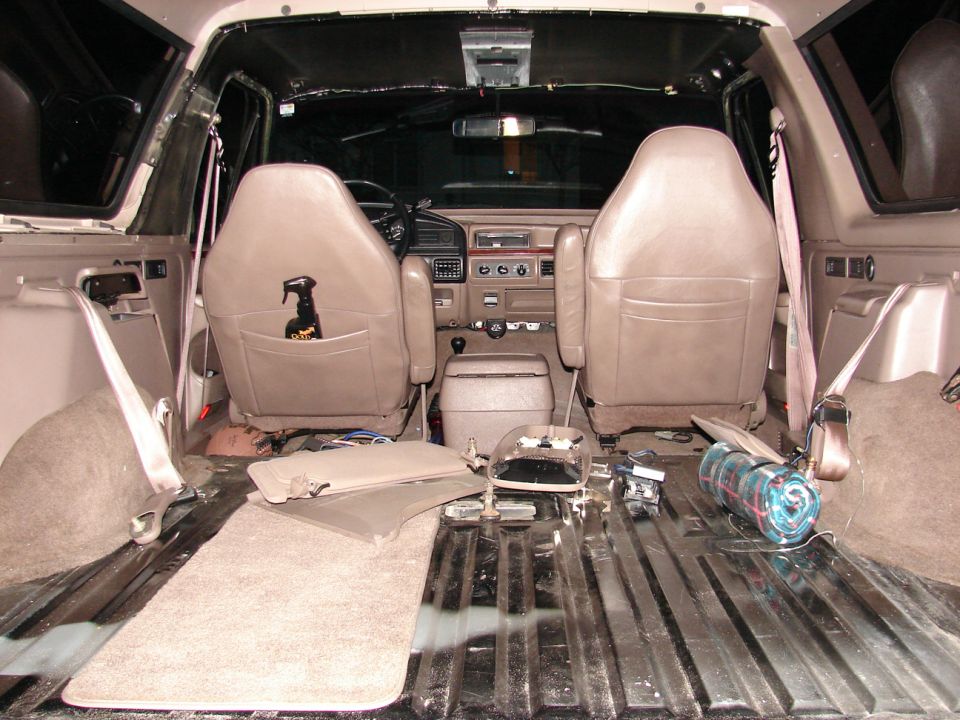 SUV interior from cargo area with rear seat removed, tan buckets and bare floor