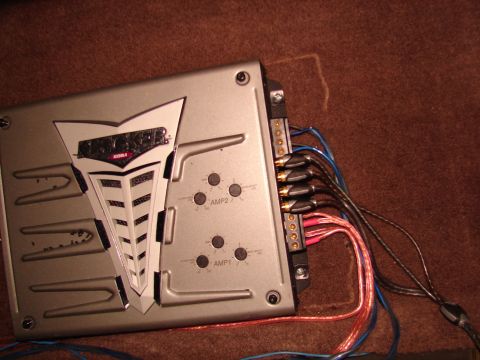 1996 Ford Bronco - A silver car amplifier with the Kicker logo is shown, connected to various wires.