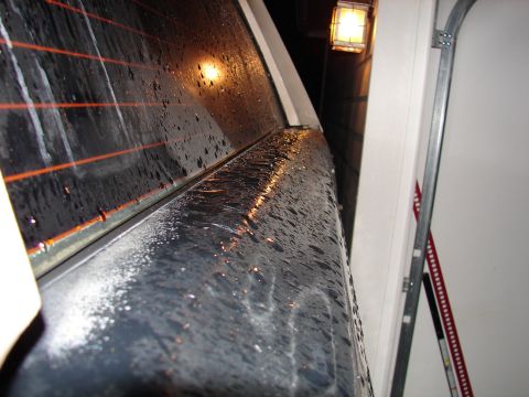1996 Ford Bronco - Water droplets cover the rear window and body panel of a vehicle parked indoors.