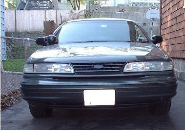 1997 Ford Crown Victoria - Frontal view of a dark green Ford Crown Victoria, showing its grille and headlights.