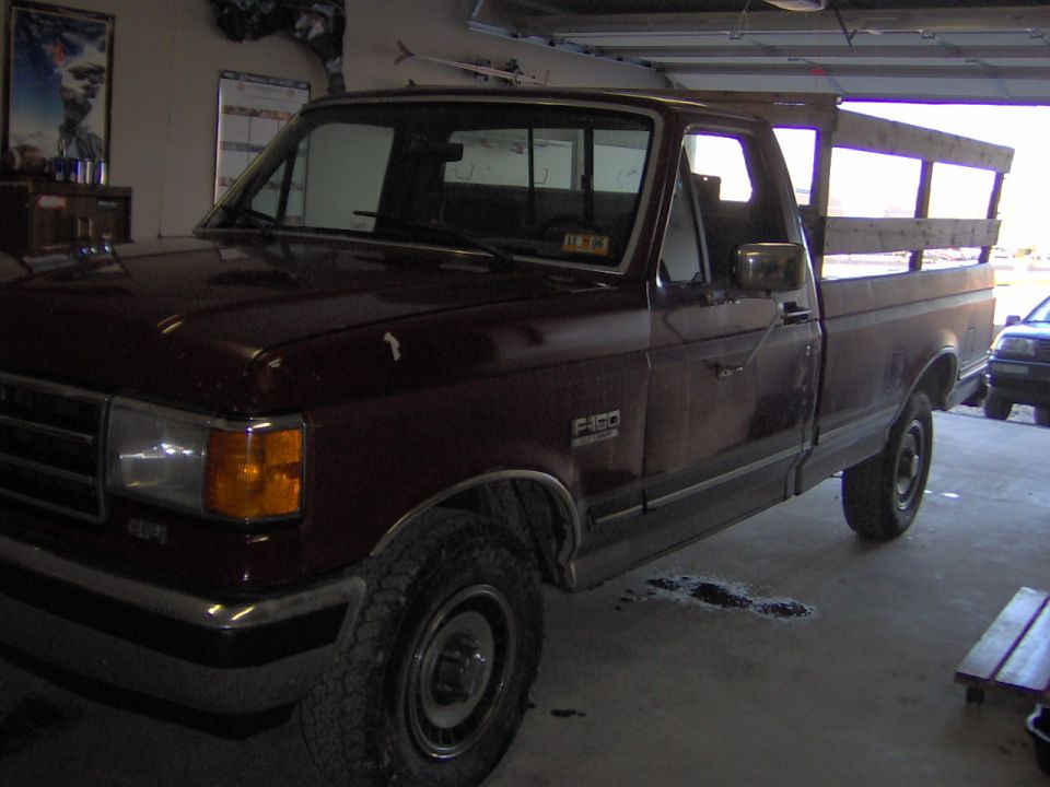 Maroon 1991 Ford F-150 pickup truck with wooden bed rails, parked indoors